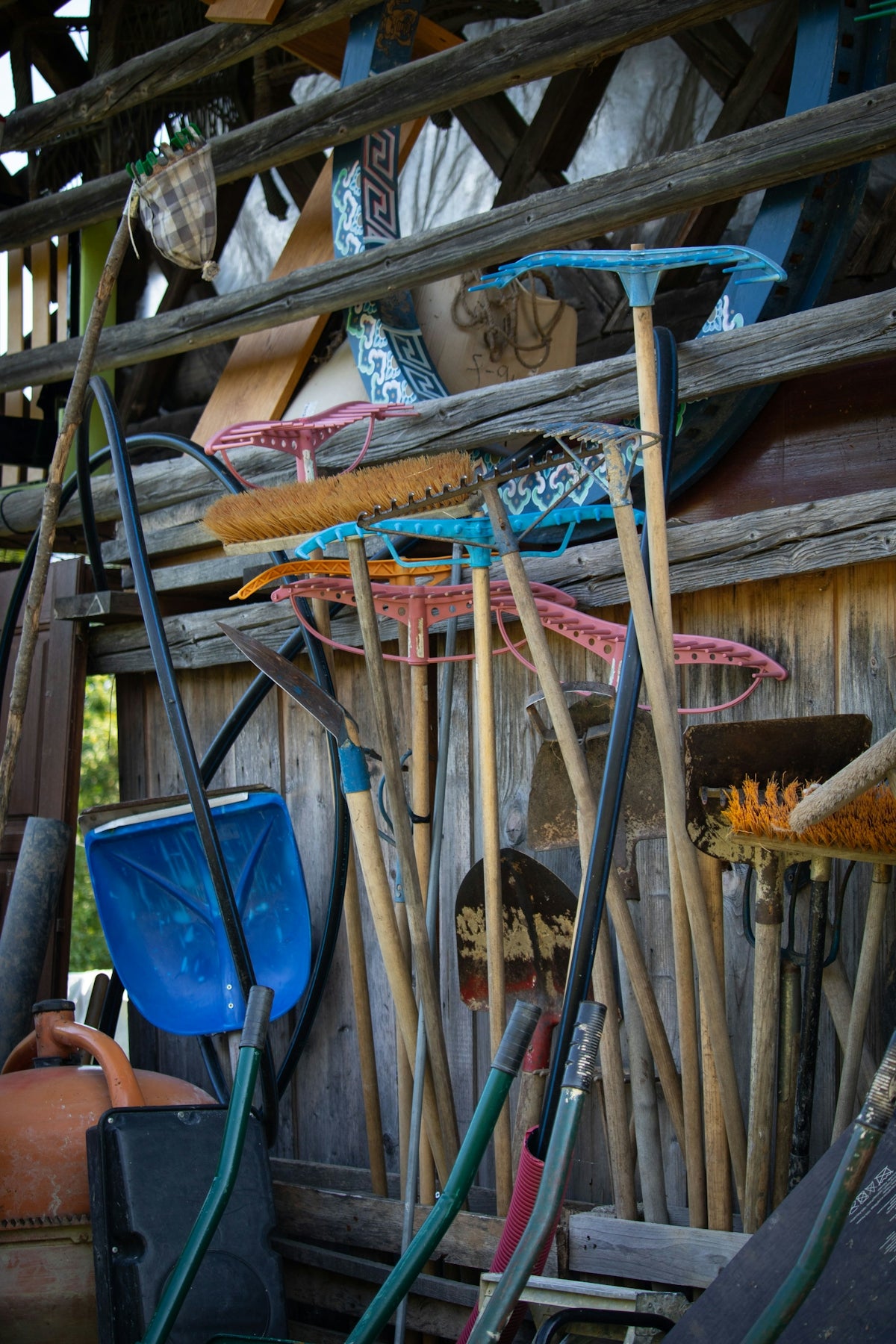 Various gardening tools leaning against a wooden wall