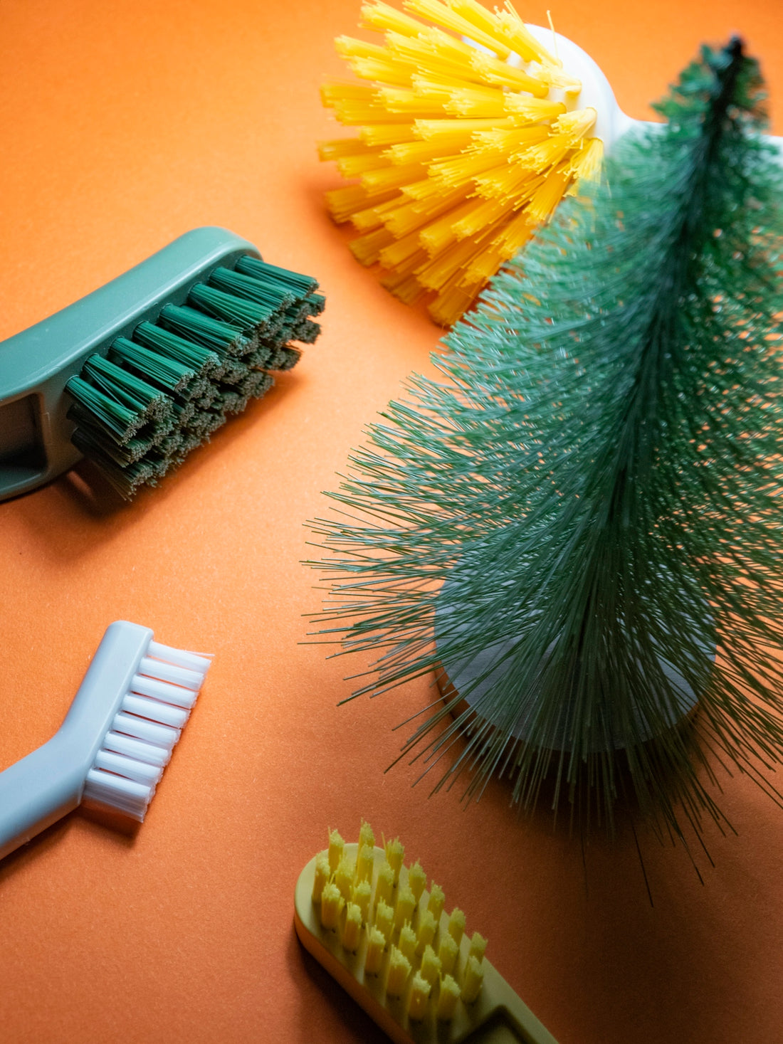 Various cleaning brushes on an orange background