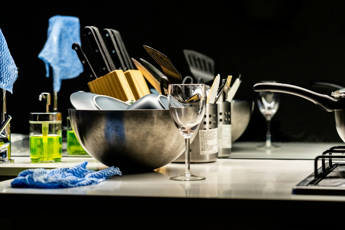 A kitchen sink with dishes and cleaning supplies