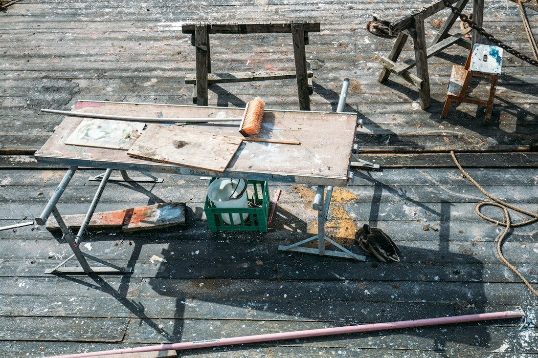 Messy outdoor wooden workspace with tools and debris